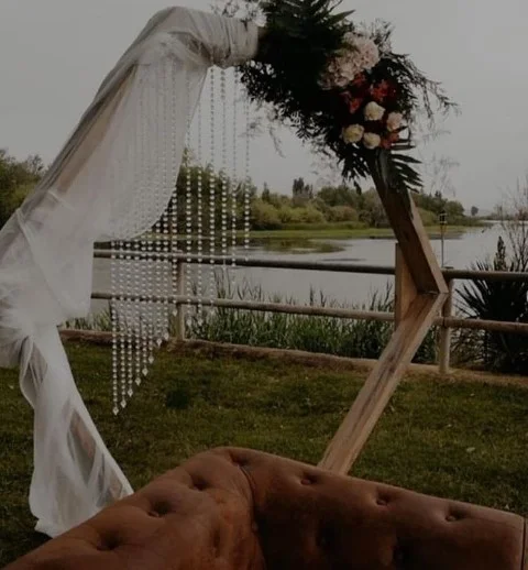 Aarreglos florales para una boda al aire libre, con un arco decorado con flores y follaje, creando un ambiente romántico y natural